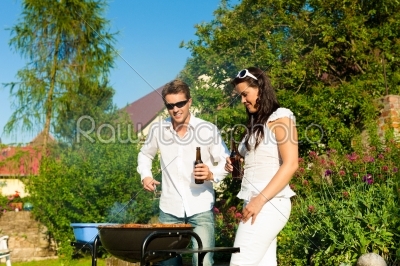 Couple doing BBQ in garden during summer