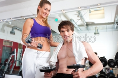 Couple exercising in gym with weights