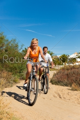 Couple in holidays cycling on beach