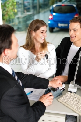 Couple signing sales contract at car dealer