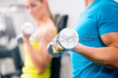 Couple training for fitness in gym with weights