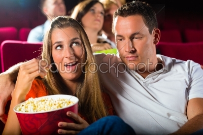 couple watching movie at movie theater and eating popcorn