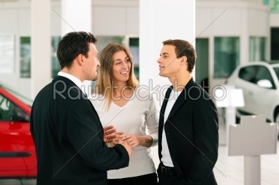 Couple with salesman at car dealer 