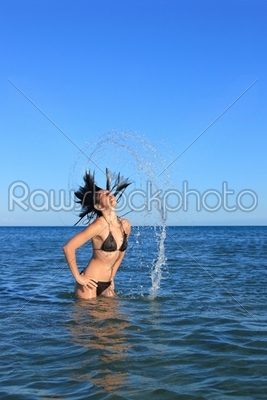 cute girl on the beach splashing out of the water