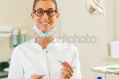 Dentist in her surgery hold mirror and scraper