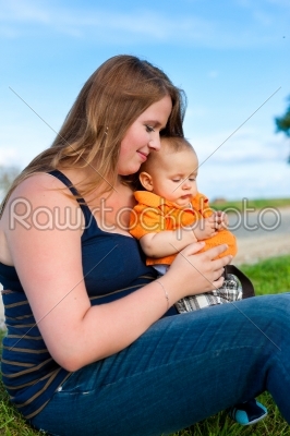 Family - mother and child sitting on a meadow