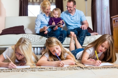 Family at home, the children coloring on floor
