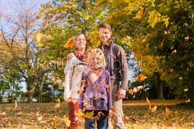 Family in front of colorful trees in autumn or fall