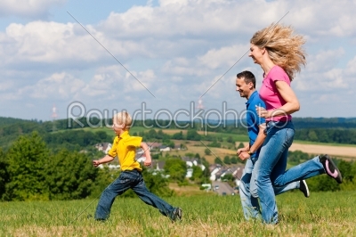 Family playing tag on meadow in summer 