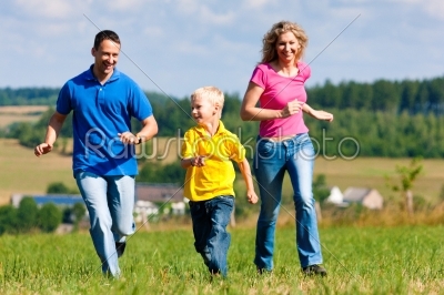 Family playing tag on meadow in summer