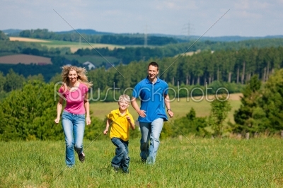 Family running on meadow in summer 