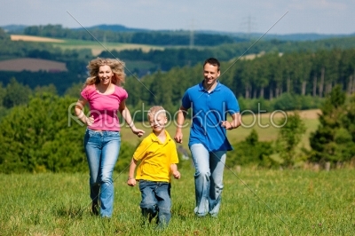 Family running on meadow in summer 