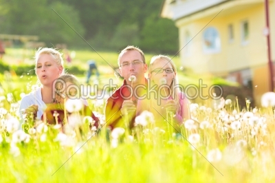family sitting in meadow in front of home