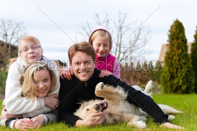 Family sitting with dogs together on a meadow