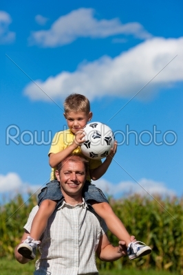 Family with children and football on a meadow