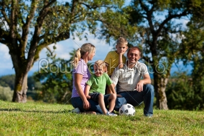 Family with children and football on a meadow