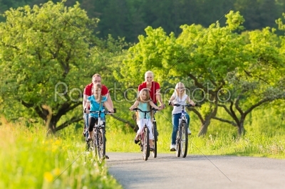 Family with kids cycling in summer with bicycles