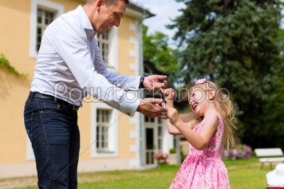 Father is playing with his daughter on a meadow