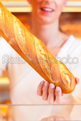 Female baker in her bakery with baguette