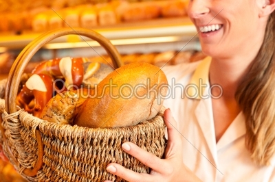 Female baker selling bread by basket in bakery