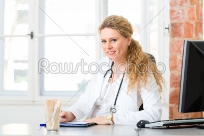 Female doctor writing document on desk in clinic