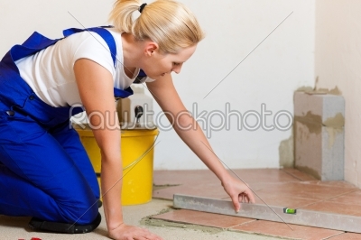 Female tiler tiling tiles on the floor