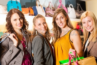 Four female friends shopping bags in a mall
