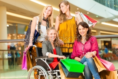 Four female friends shopping in a mall with wheelchair