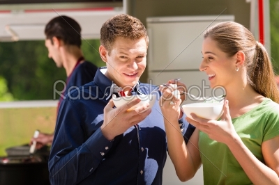 Friends eating a soup on the food stall