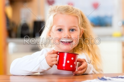 Girl drinking milk in kitchen  