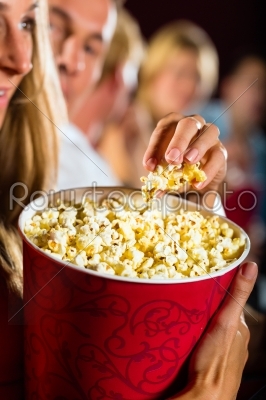Girl eating popcorn in cinema or movie theater