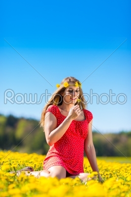 Girl in spring on a flower meadow with dandelion