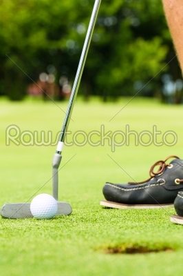 Golf player putting ball in hole