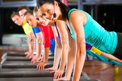 Group of people and instructor in gym stretching 