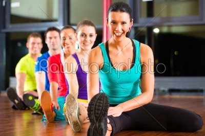 Group of people and instructor in gym stretching