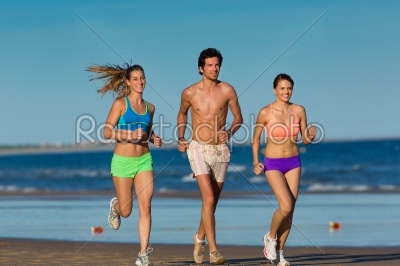 Group of sport people - man and women - jogging on the beach