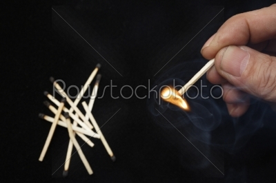 Hand holding burning match stick on black background 