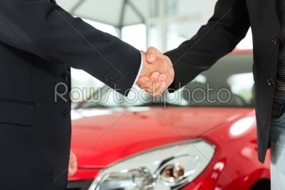 Handshake of two men in suits with a red car