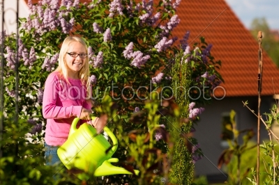Happy child watering flowers in  the garden