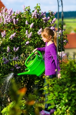 Happy child watering flowers in the garden