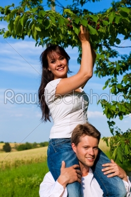 Happy couple eating cherries in summer