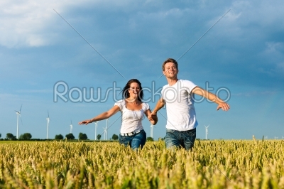 Happy couple running over grainfield