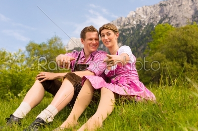 Happy couple sitting in Alpine meadow 