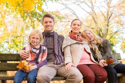 Happy Family outdoors sitting on bench in autumn