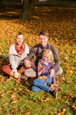 Happy Family outdoors sitting on grass in autumn