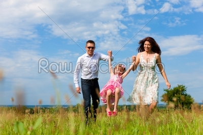 Happy family running on meadow in summer