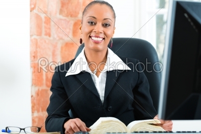 Lawyer in office with law book and computer