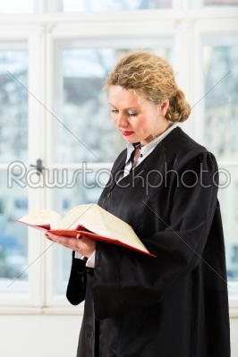 Lawyer in office with law book reading by window