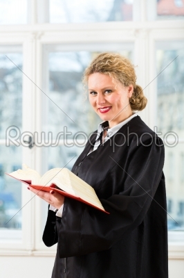 Lawyer in office with law book reading by window