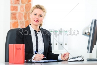 Lawyer in office with law book working on desk